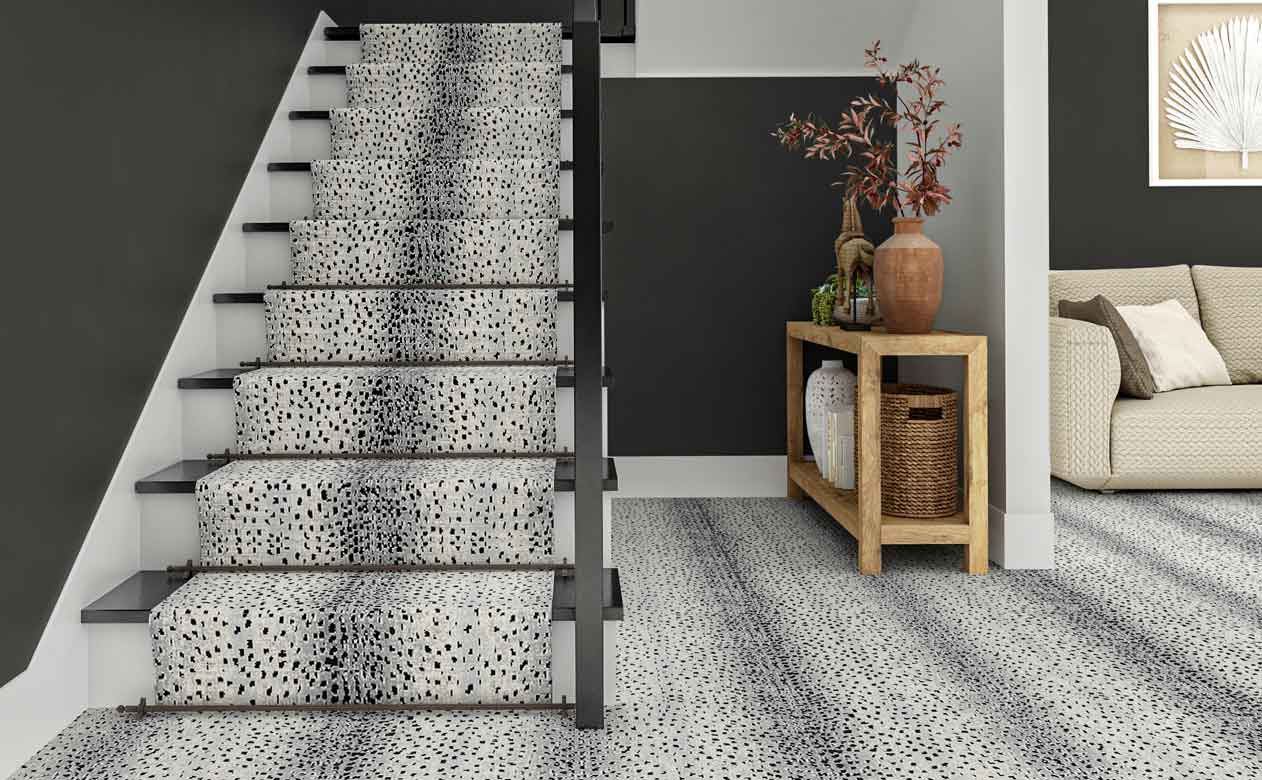 animal print grey carpet in enryway with staircase, grey walls and wood entryway table